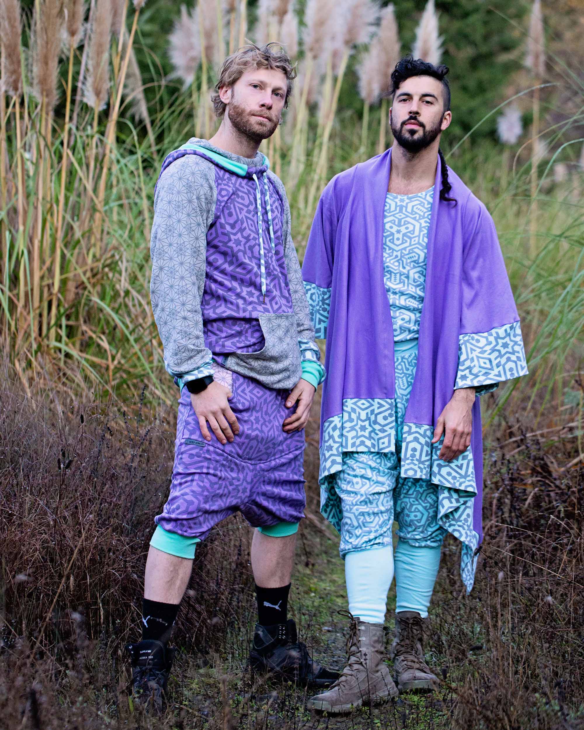 Two male models wearing Sacred Geometrix garments, lavender and grey fabric with geometric prints.
