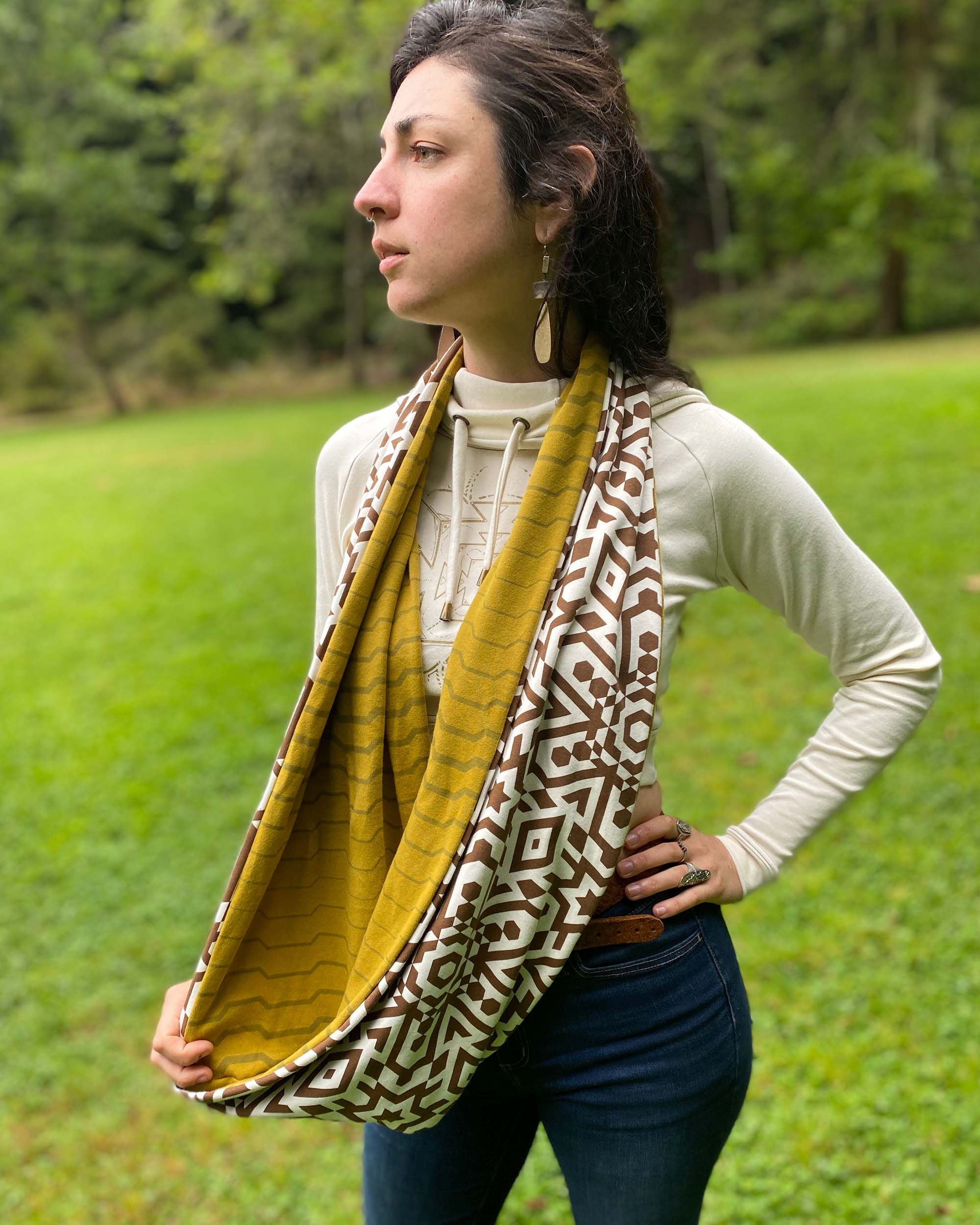 Un-dyed and yellow organic cotton infinity scarf with geometric prints, left side view on female model.