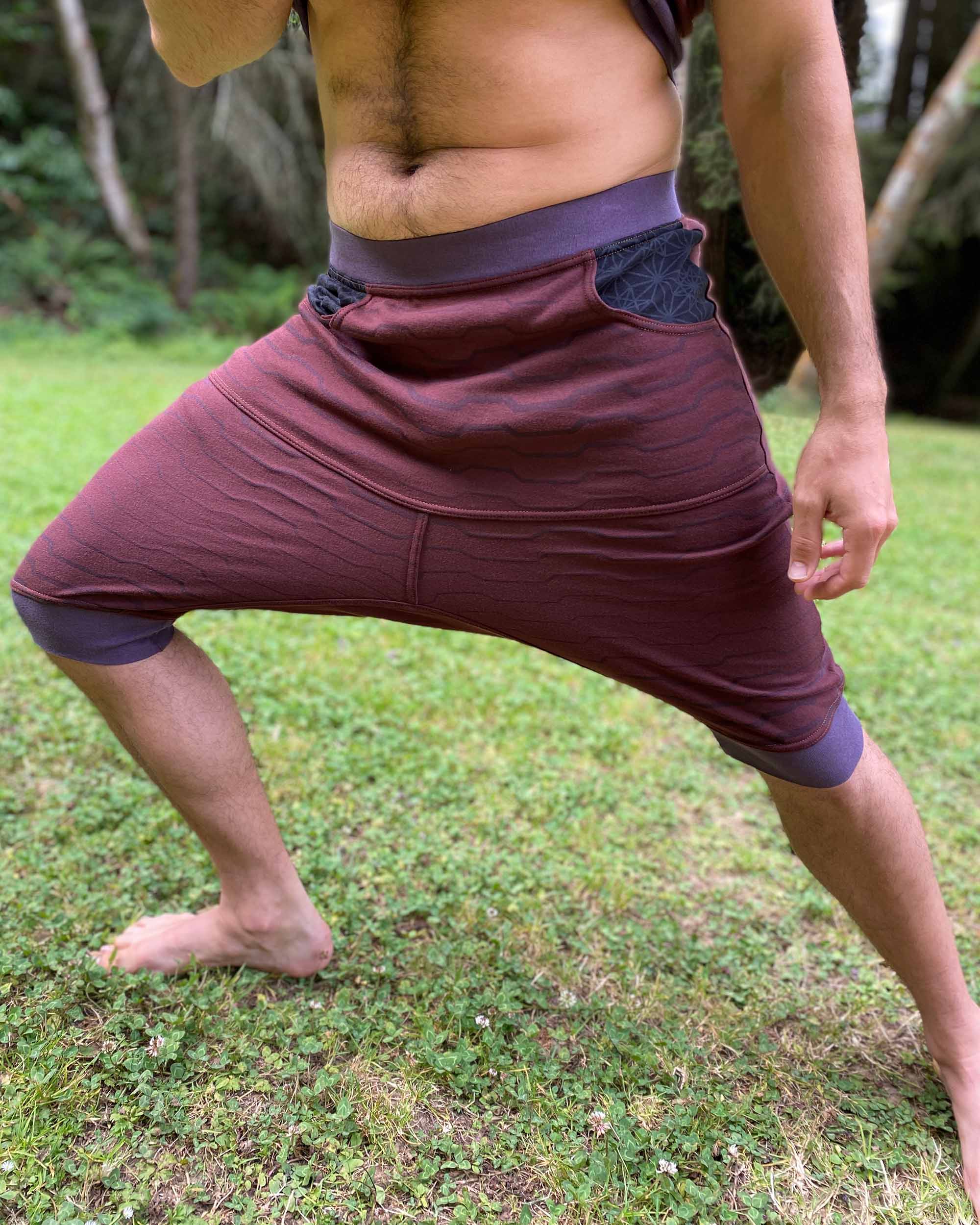 Organic cotton drop crotch shorts, brown fabric with geometric print, front right view on stretching model.  