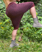 Organic cotton drop crotch shorts, brown fabric with geometric print, front view on male model stretching.