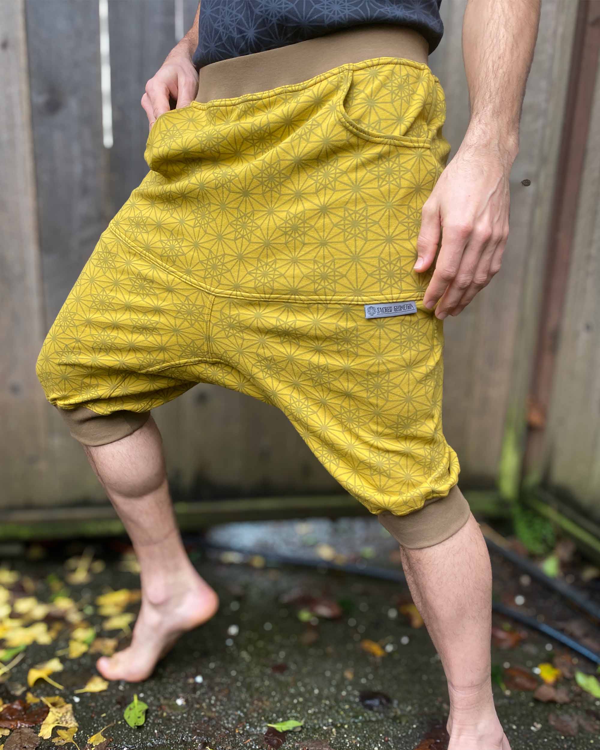 Organic cotton drop crotch shorts, yellow fabric with geometric print, front left side view on model.