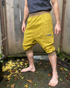 Organic cotton drop crotch shorts, yellow fabric with geometric print, left side view on model.