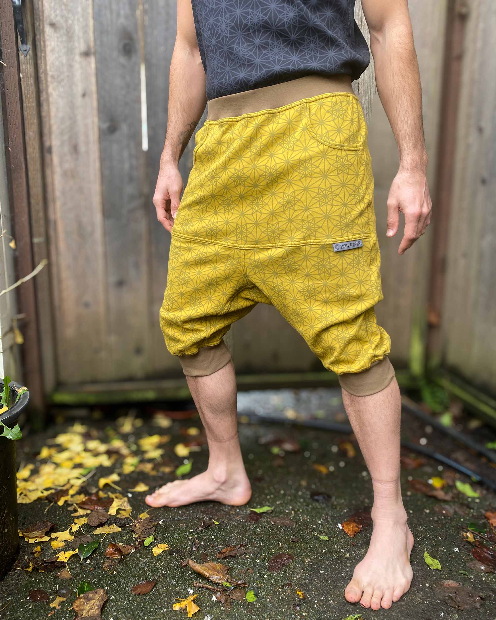 Organic cotton drop crotch shorts, yellow fabric with geometric print, left side view on model.