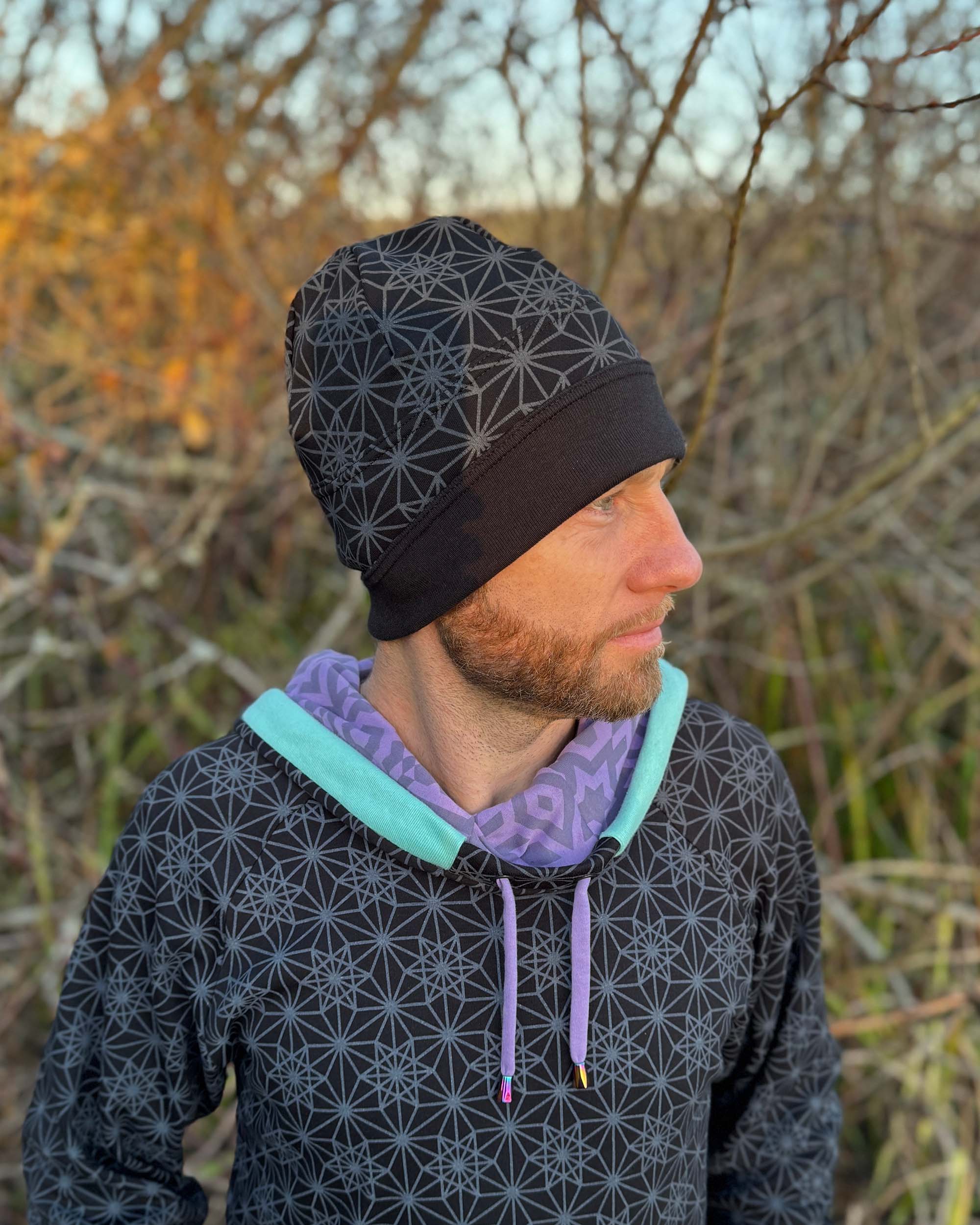 Organic cotton beanie, black fabric with sacred geometry print, right side on male model.