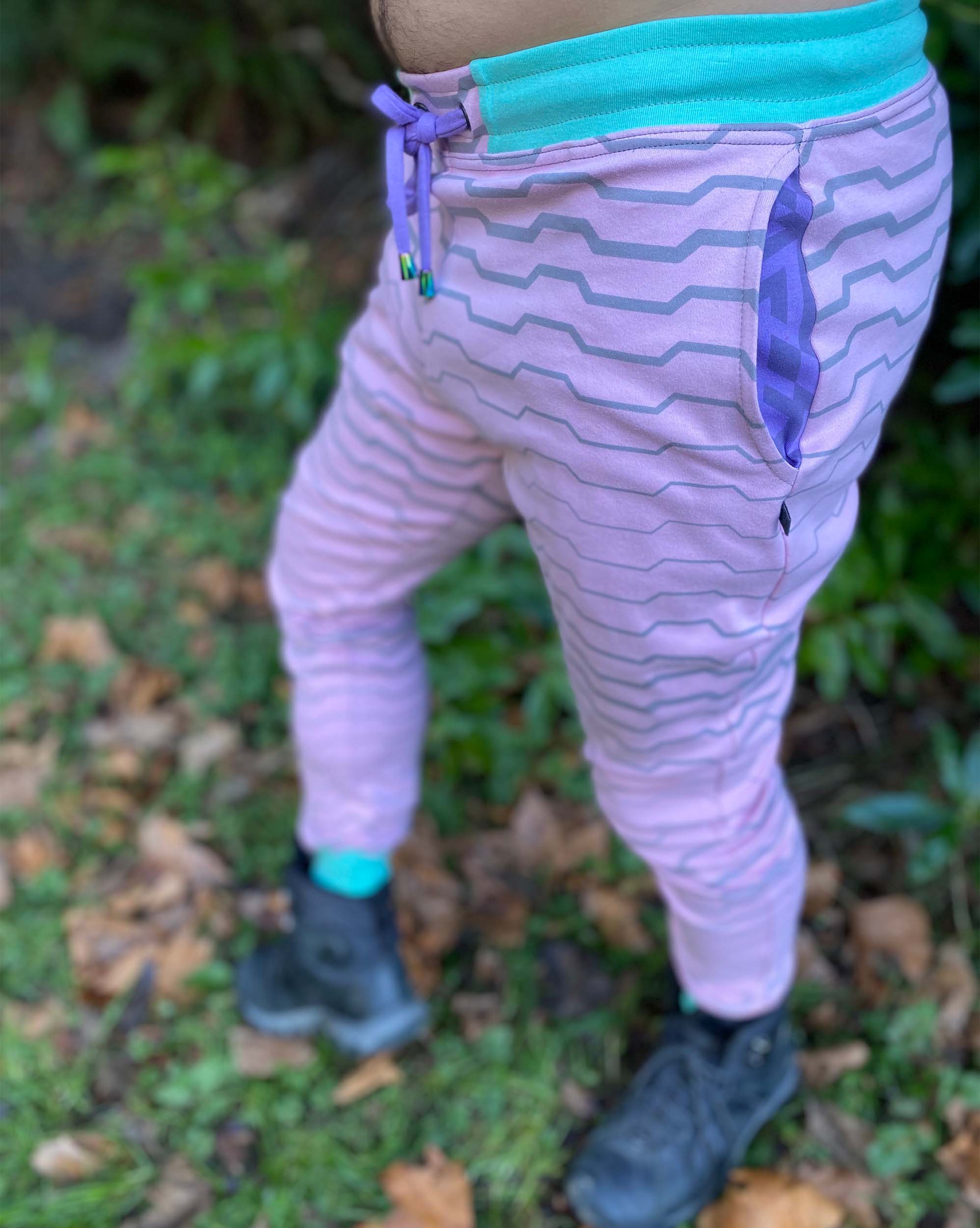 Men's organic cotton joggers, pink and purple fabric, geometric stripe print, side view on model.